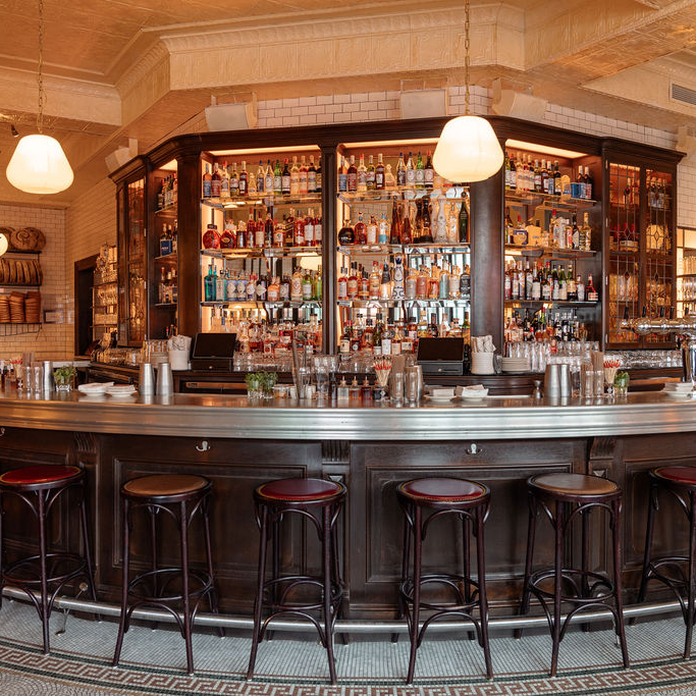 Curved bar with high stools, glassware, and a well-stocked back bar behind.